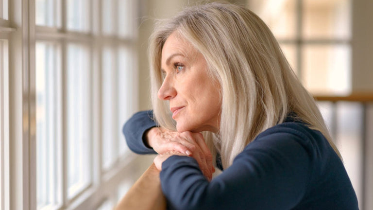 "Kvinde i overgangsalderen reflekterer ved vinduet, mens hun overvejer fordele ved isbad til lindring af symptomer.